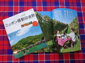 赤、青、白のタータンチェック生地の上に置かれたニッポン感動田舎旅の本の写真